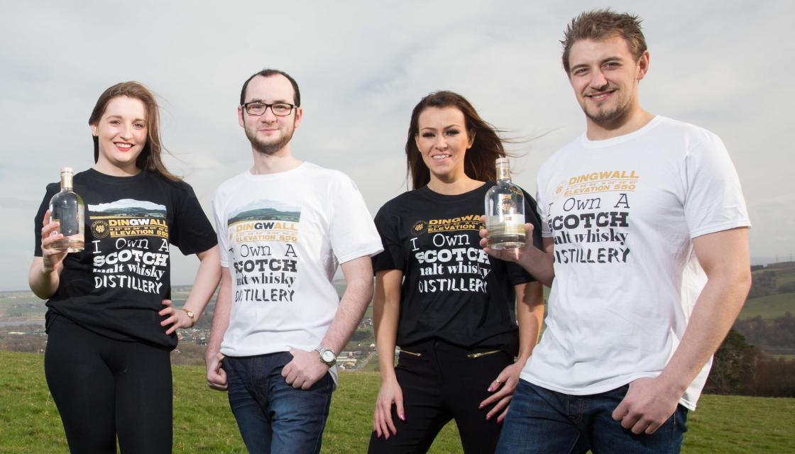 Four members of Glenwvis Distillery holding bottles of whiskey