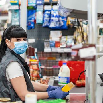 Women serving customers in shop wearing a mask