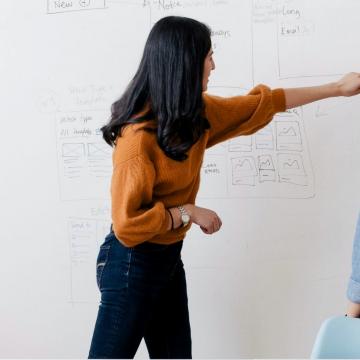 Two woman working at a whiteboard
